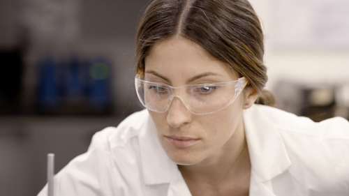 an engineering masters student in the laboratory wearing protective glasses and lab coat