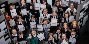 photo taken from above of school children holding primary engineer award certificates and looking up