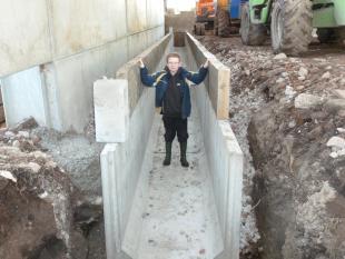 Tom Corlett standing inside an unfinished concrete slurry channel on a farm
