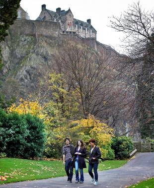 University of Edinburgh students walking through Princes Street Gardens with Edinburgh Castle in background