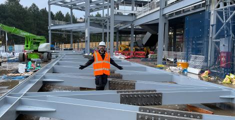 Hussein standing between steel beams on the Nucleus building construction site within King's Buildings